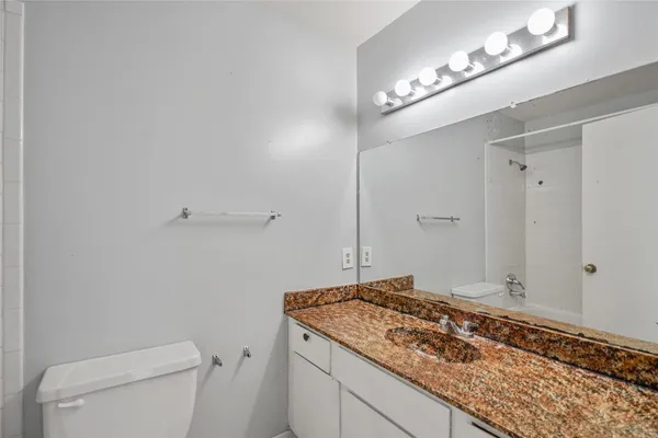a bathroom with a granite countertop sink and a toilet