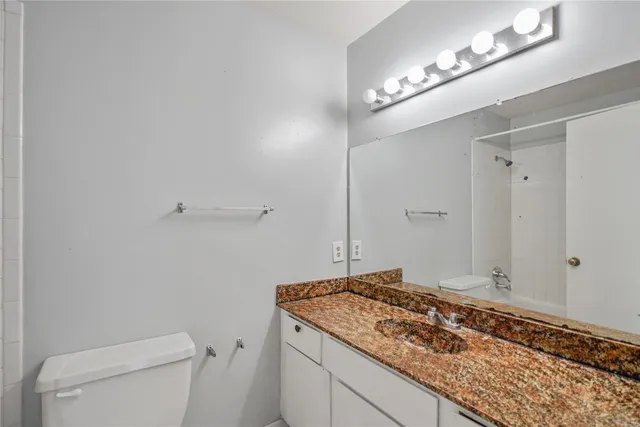 a bathroom with a granite countertop sink and a toilet