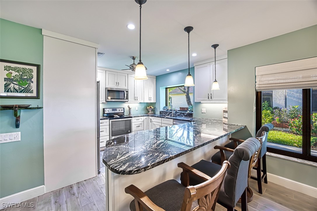 1683 Bent Tree Circle Fort Myers, FL 33907 - Photo 15 of 48 a kitchen with kitchen island a dining table chairs and a wooden floor