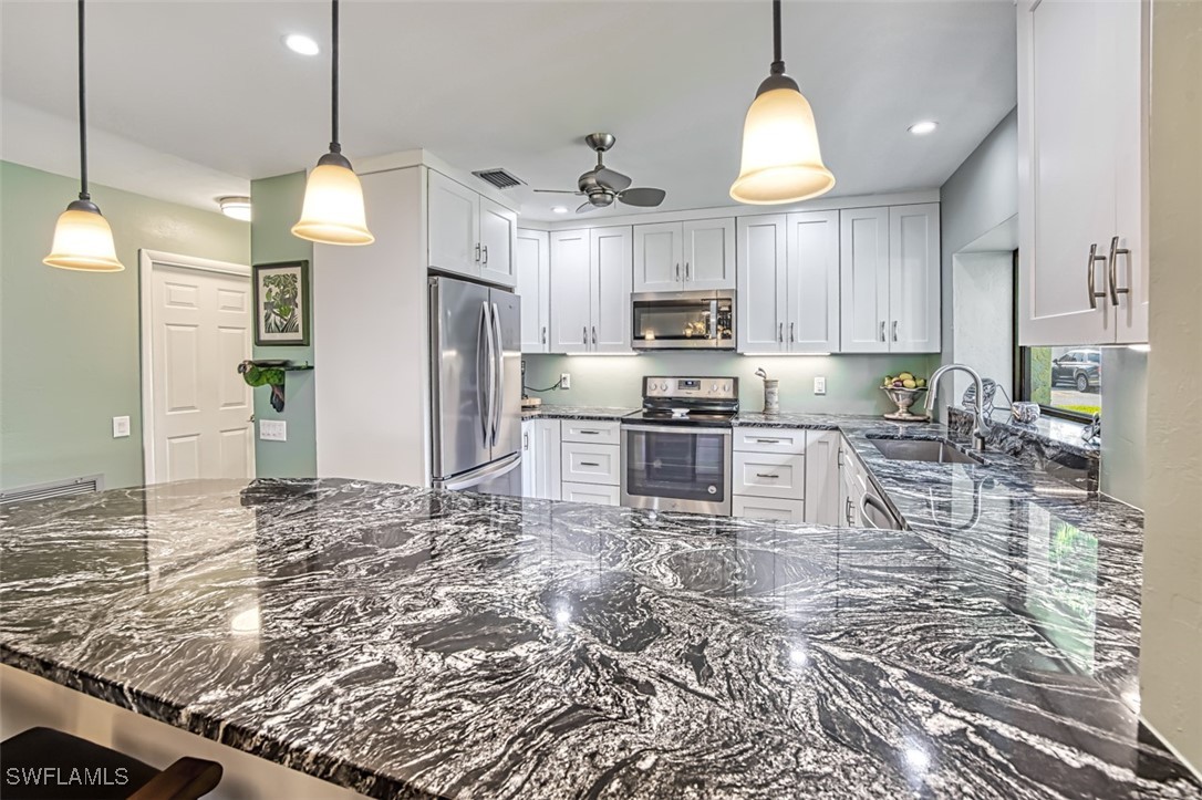 1683 Bent Tree Circle Fort Myers, FL 33907 - Photo 16 of 48 a kitchen with kitchen island granite countertop a sink cabinets and stainless steel appliances