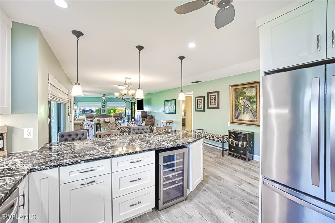 1683 Bent Tree Circle Fort Myers, FL 33907 - Photo 18 of 48 a kitchen with stainless steel appliances granite countertop a refrigerator a sink dishwasher and white cabinets with wooden floor