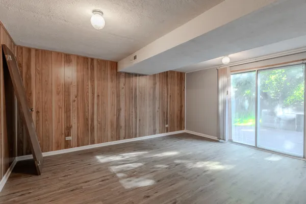 a view of an empty room with wooden floor and a window