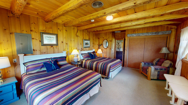 315 Abbey Road Moab, UT 84532 - Photo 11 of 46 Bedroom featuring electric panel, a wooden ceiling with exposed beams, light carpet, and wood walls