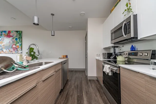 a kitchen with stainless steel appliances granite countertop a sink a stove top oven and wooden floor