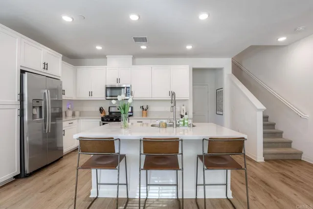 a kitchen with stainless steel appliances kitchen island granite countertop a refrigerator and a stove top oven with wooden floor