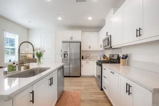 a kitchen with white cabinets a sink and stainless steel appliances
