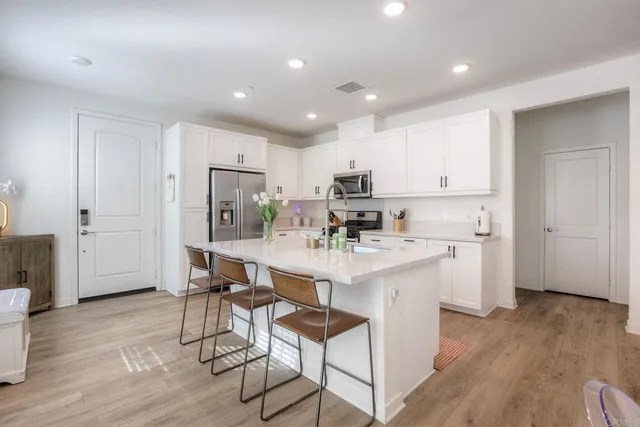 a kitchen with stainless steel appliances kitchen island granite countertop a refrigerator and a stove top oven