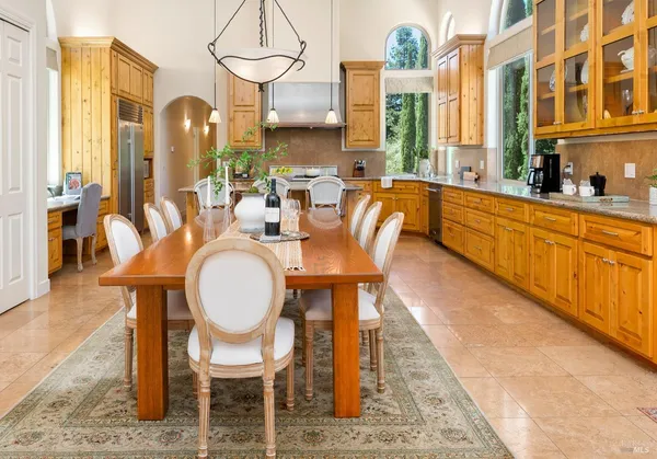 a dining room with stainless steel appliances kitchen island granite countertop a table chairs and a couch