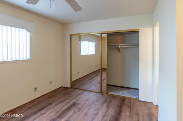 an empty room with wooden floor closet and windows