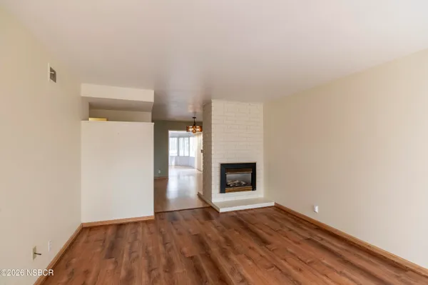 a view of empty room with wooden floor and a fireplace