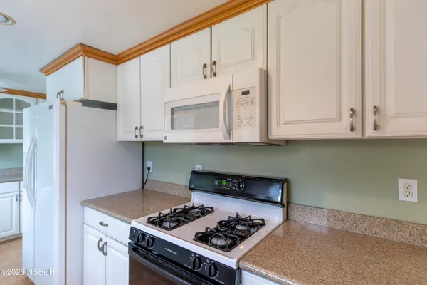 a kitchen with stainless steel appliances granite countertop a stove a refrigerator and a white cabinets