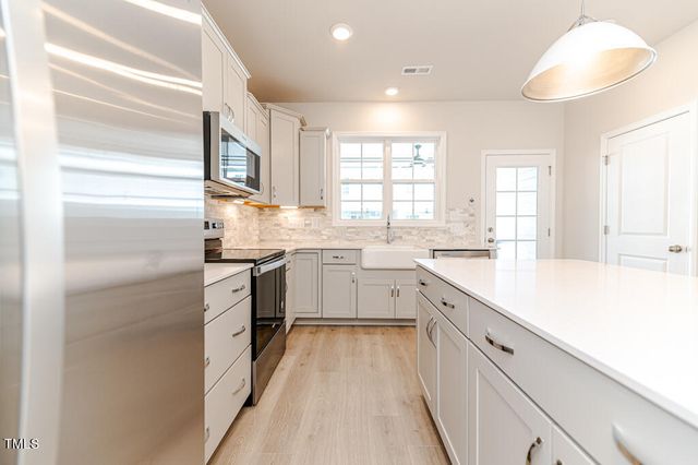a kitchen with a sink dishwasher a stove and white cabinets with wooden floor