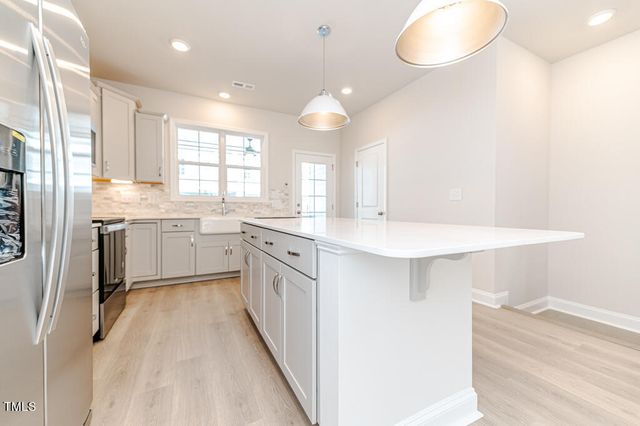 a kitchen with white cabinets appliances and a window