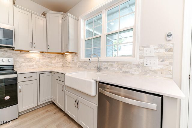a kitchen with stainless steel appliances white cabinets and a window