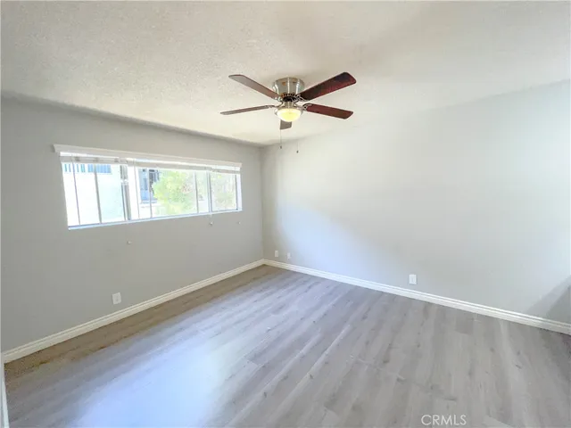 an empty room with wooden floor ceiling fan and windows