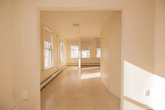 a view of a hallway with wooden floor and a bathroom