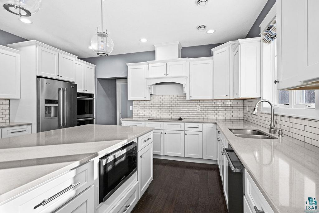 3879 Okerstrom Road Hermantown, MN 55811 - Photo 7 of 32 Kitchen with light stone countertops, stainless steel appliances, white cabinets, and pendant lighting