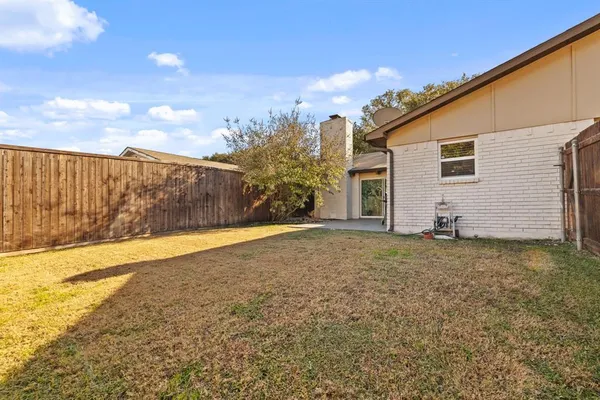 a view of a yard in front of a house with plants and large tree