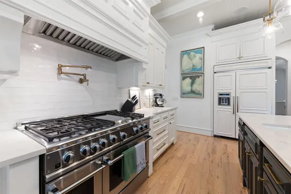 a kitchen with stainless steel appliances a stove a sink and wooden floor