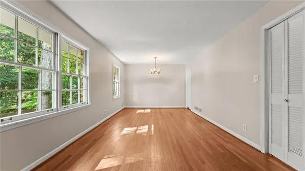 a view of an empty room with wooden floor and a window