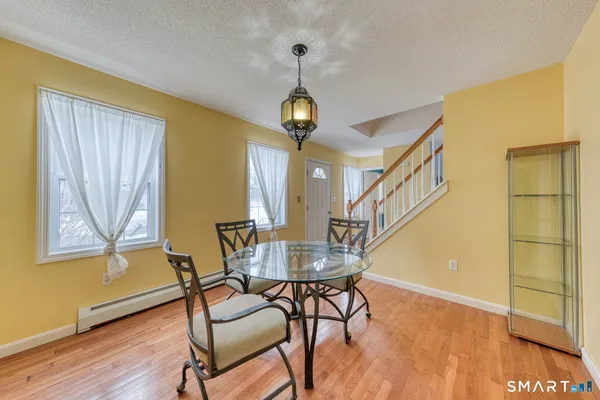 a dining room with wooden floor a chandelier a wooden table and chairs