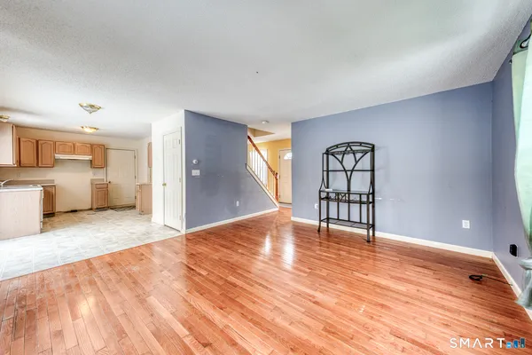 a view of an empty room with window and wooden floor