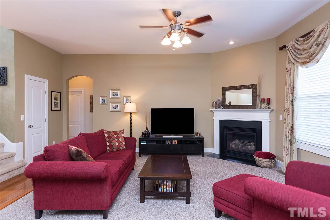10121 Darling Street Raleigh, NC 27613 - Photo 4 of 25 a living room with furniture a fireplace and a flat screen tv