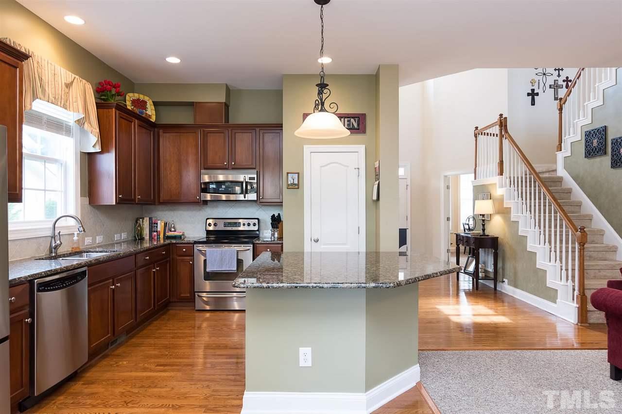 10121 Darling Street Raleigh, NC 27613 - Photo 7 of 25 a kitchen with stainless steel appliances granite countertop a refrigerator a sink dishwasher a stove and white cabinets with wooden floor