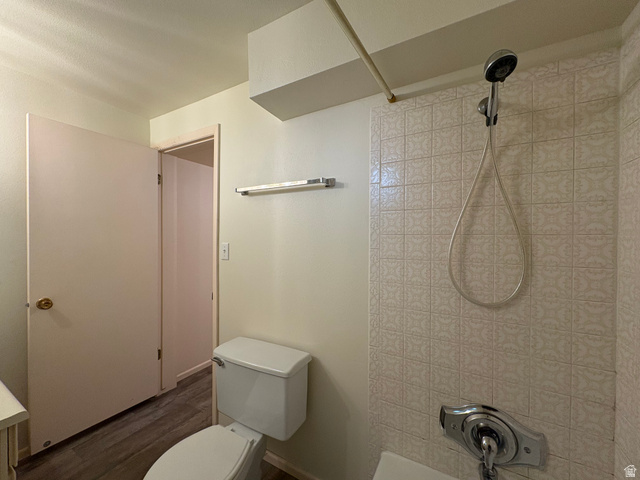 595 Meadowlark Road Orem, UT 84097 - Photo 63 of 87 Bathroom featuring patterned shower tiling, white toilet, chrome fixtures, and wood-finish flooring