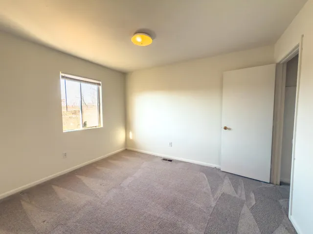 an empty room with a chandelier fan and windows