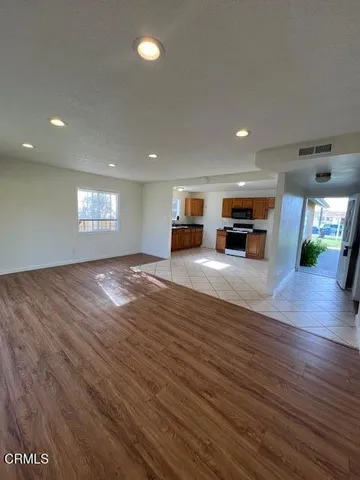 an empty room with wooden floor fireplace and windows