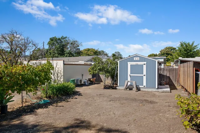 a view of a house with a yard and large trees