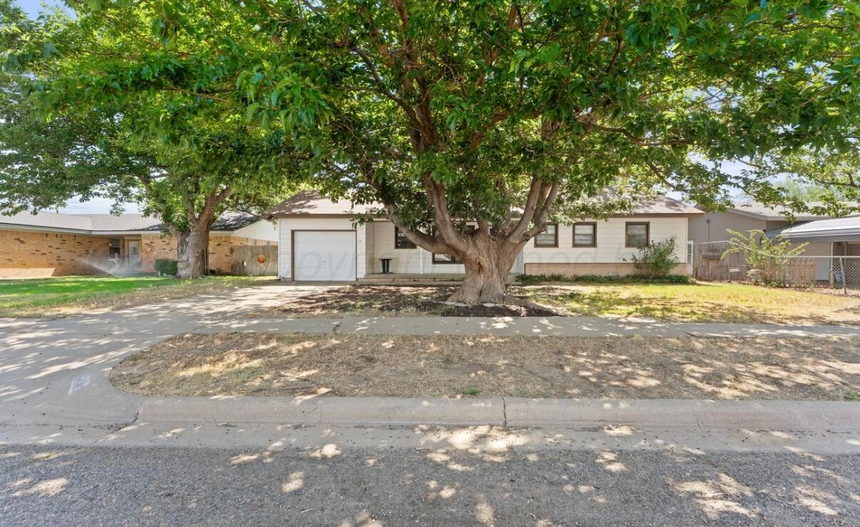 a front view of a house with a yard and large trees