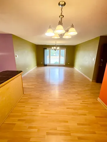 a view of an empty room with window and a kitchen
