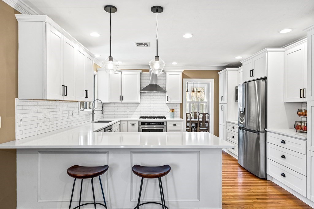 20 Walnut Street Needham, MA 02492 - Photo 4 of 27 a kitchen with stainless steel appliances granite countertop a sink a stove a refrigerator and island with wooden floor
