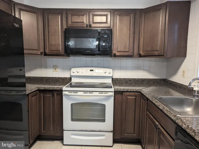 a kitchen with granite countertop a stove microwave and sink