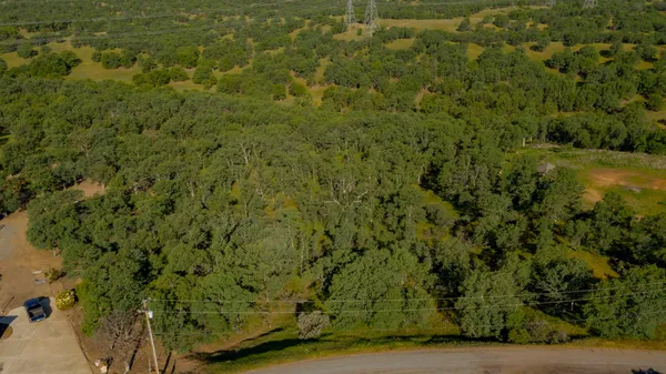 an aerial view of residential houses with outdoor space and trees
