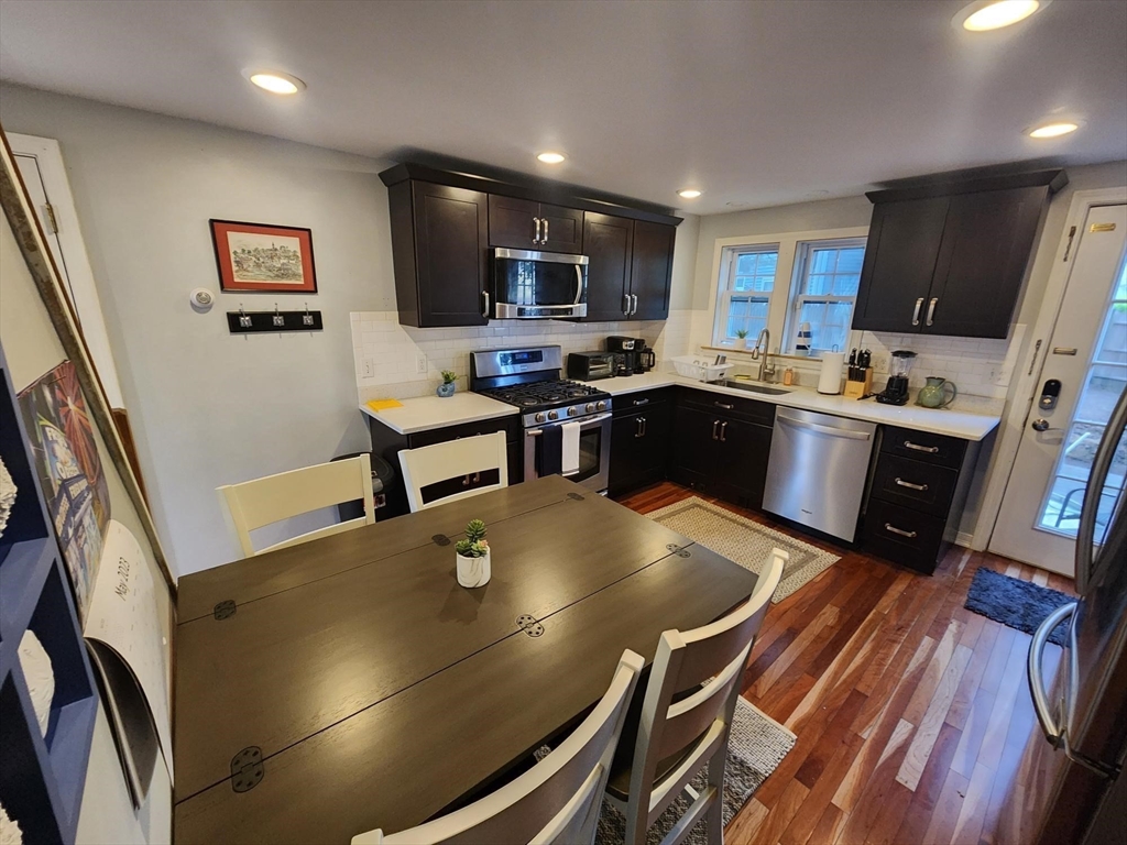 57 Green Street Marblehead, MA 01945 - Photo 2 of 29 a kitchen with stainless steel appliances granite countertop a stove a refrigerator a sink dishwasher a dining table and chairs with wooden floor