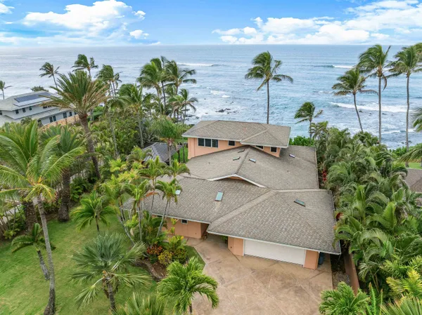 an aerial view of a house with a yard and ocean view
