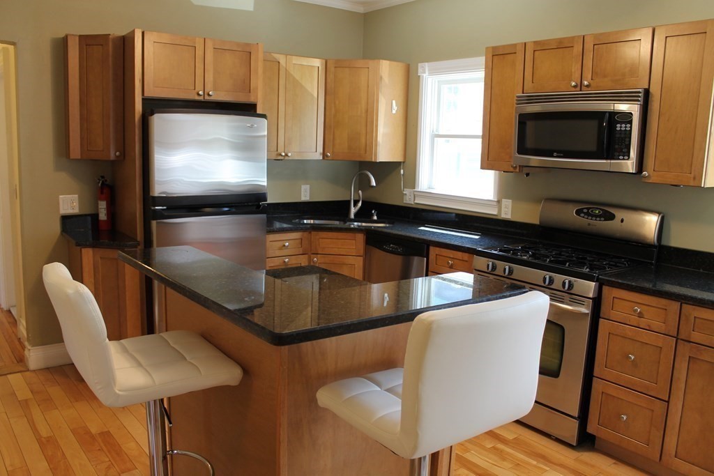 a kitchen with stainless steel appliances granite countertop a sink a microwave refrigerator and chairs
