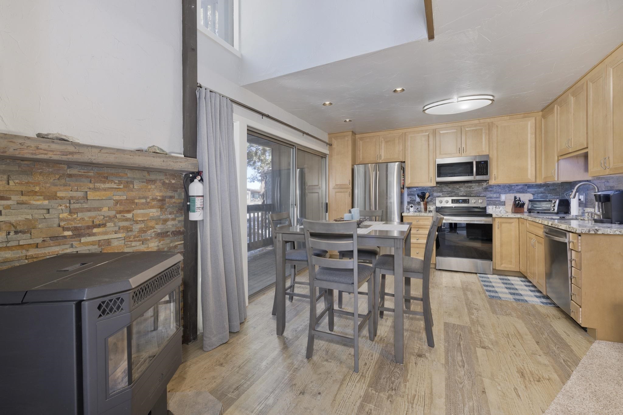 Kitchen featuring light wood finish cabinetry, stainless steel appliances, light wood-style flooring, light stone countertops, and backsplash