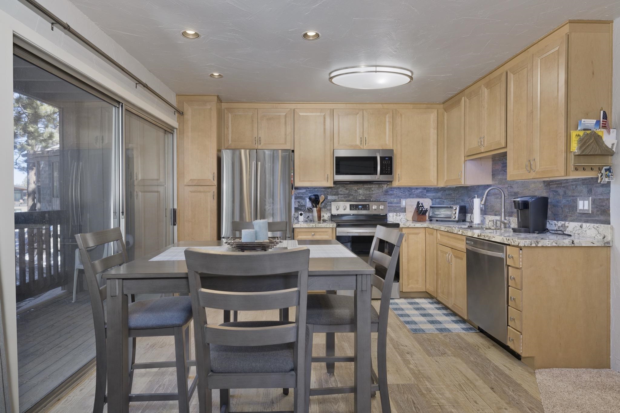 286 Old Mammoth Road, Unit 37 Mammoth Lakes, CA 93546 - Photo 11 of 33 Kitchen with light wood finish cabinets, stainless steel appliances, light wood-style floors, light stone countertops, and backsplash