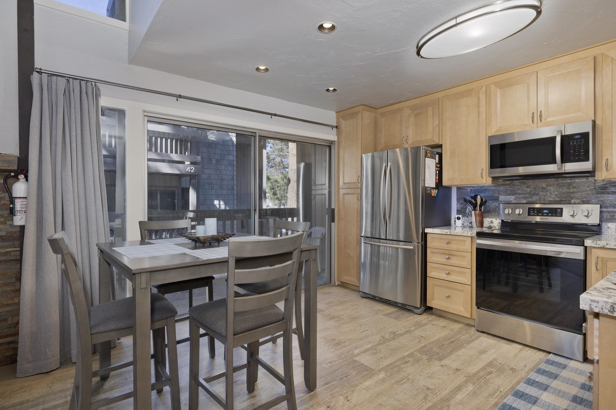 286 Old Mammoth Road, Unit 37 Mammoth Lakes, CA 93546 - Photo 12 of 33 Kitchen featuring stainless steel appliances, light wood finish cabinets, light stone counters, light wood-type flooring, and decorative backsplash