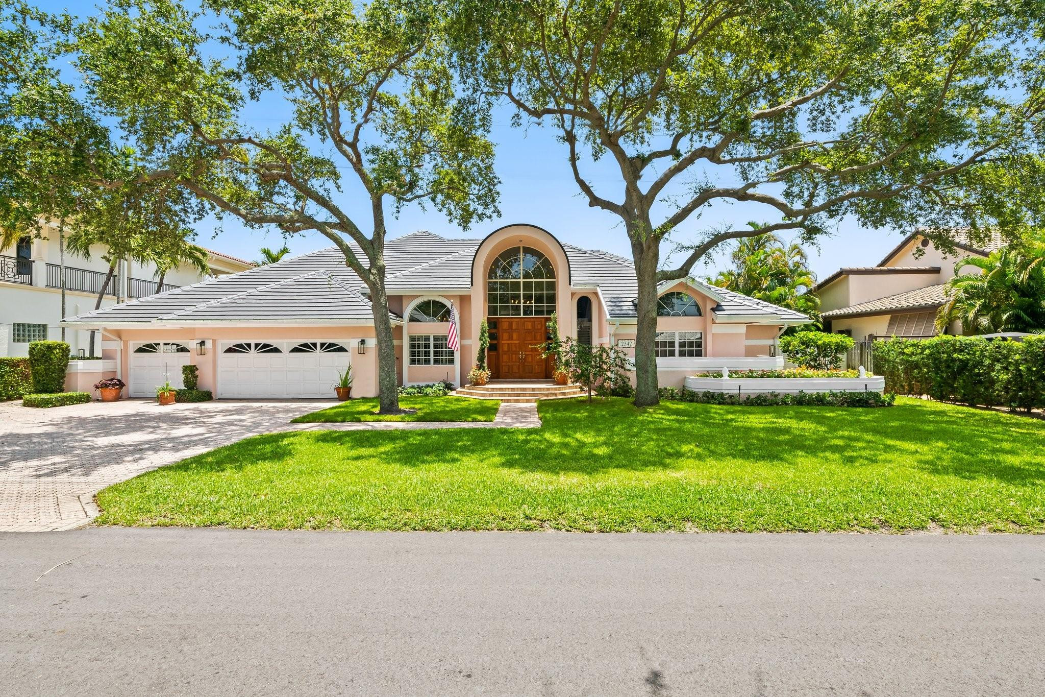2342 Northeast 26th Street Lighthouse Point, FL 33064 - Photo 42 of 45 a front view of a house with a garden and trees