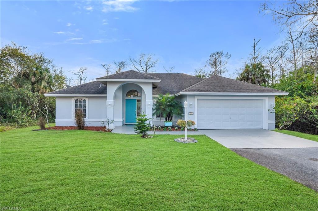 220 37th Avenue Northeast Naples, FL 34120 - Photo 1 of 49 a front view of a house with a garden and trees