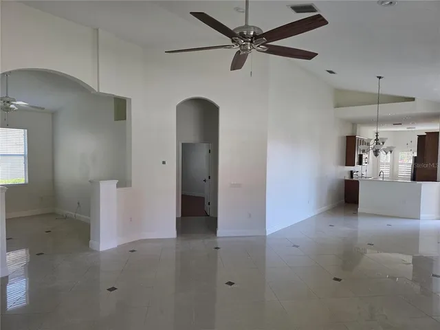 an empty room with chandelier fan and windows