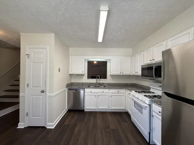 a kitchen with stainless steel appliances white cabinets and a refrigerator