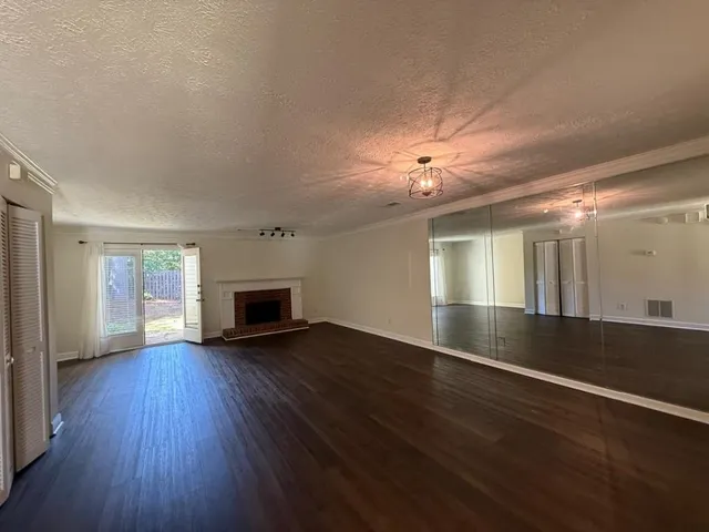 an empty room with wooden floor fireplace and windows