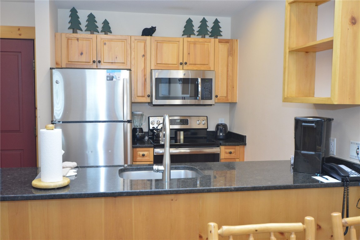 172 Copper Circle, Unit 107 Copper Mountain, CO 80443 - Photo 12 of 25 a kitchen with kitchen island granite countertop a refrigerator a stove and a sink