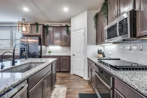 a kitchen with stainless steel appliances granite countertop a sink stove and refrigerator